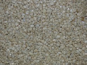 Vue rapprochée d'une surface recouverte de petites pierres claires ressemblant à du gravier.