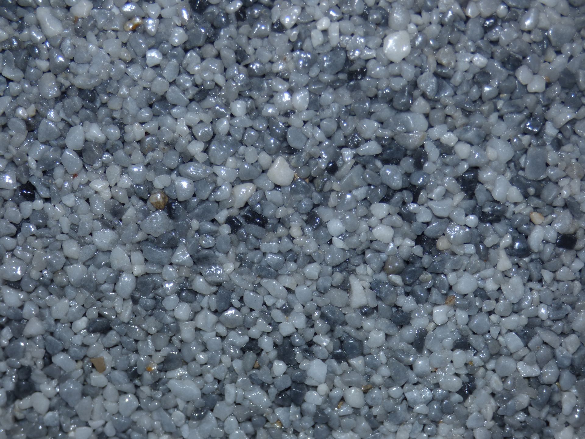 Gros plan de galets gris et brillants, de différentes nuances et tailles, remplissant le cadre.