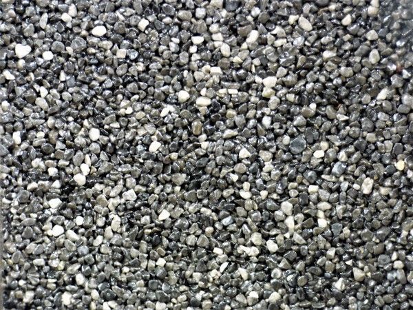 Gros plan sur du gravier gris foncé et blanc, dispersé uniformément.
