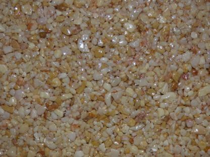 Gros plan sur une surface texturée et brillante de petits cailloux brun clair et beige.