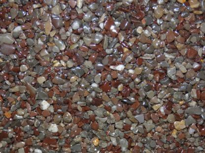 Gros plan sur des petits cailloux brillants de couleurs mélangées ; principalement rouges, bruns et gris.