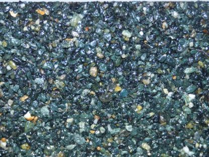 Gros plan d'une surface recouverte de petits cailloux vert foncé et beige avec un éclat brillant.