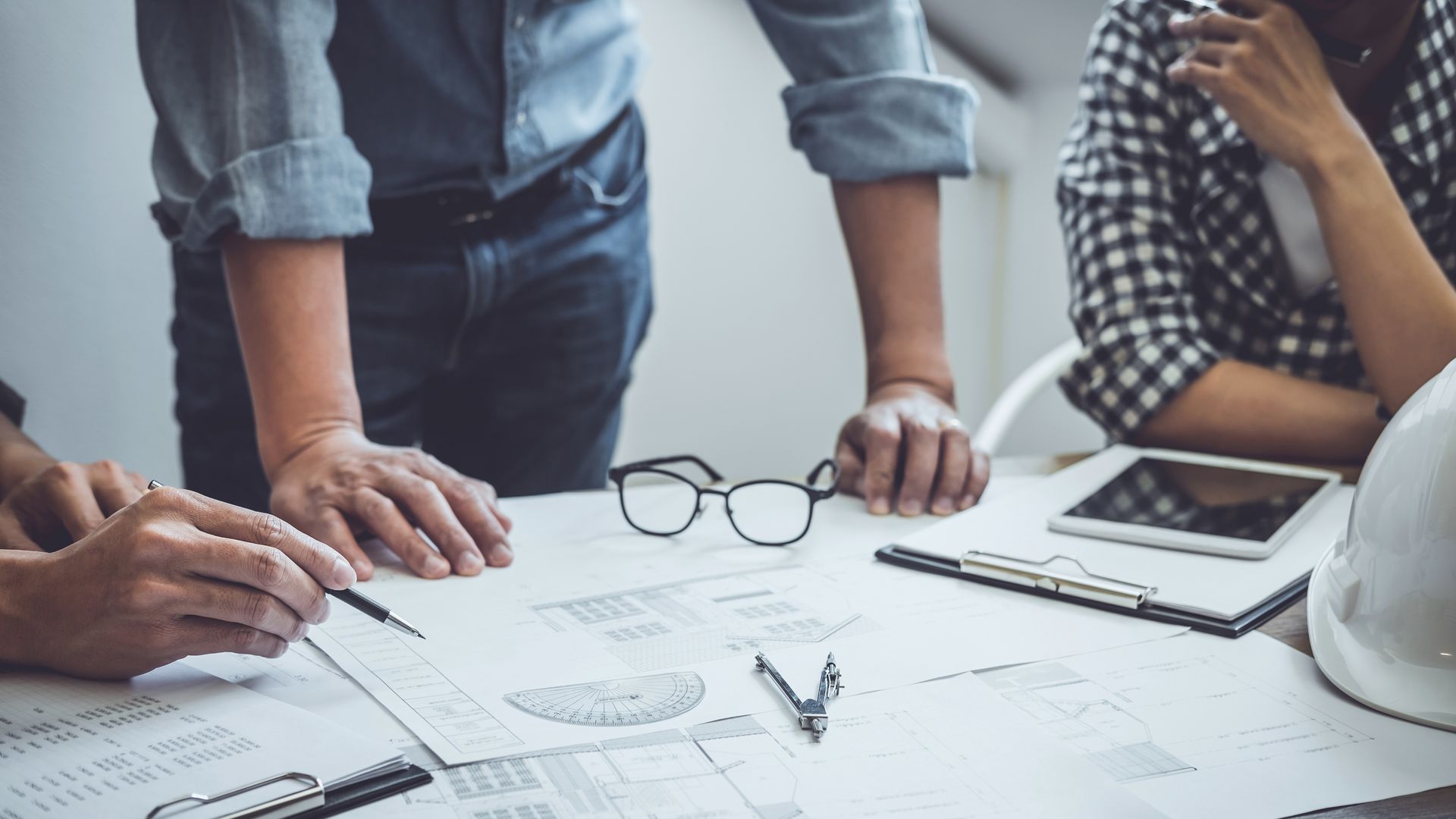 Des personnes examinent des plans sur une table ; planification technique.