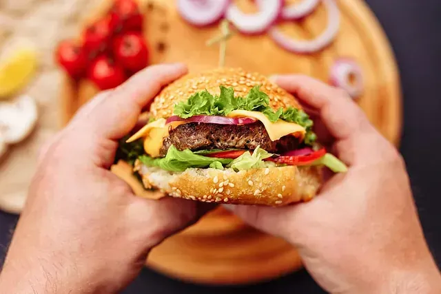 Una persona sostiene una hamburguesa en sus manos.