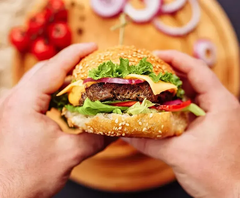 Una persona sostiene una hamburguesa en sus manos.