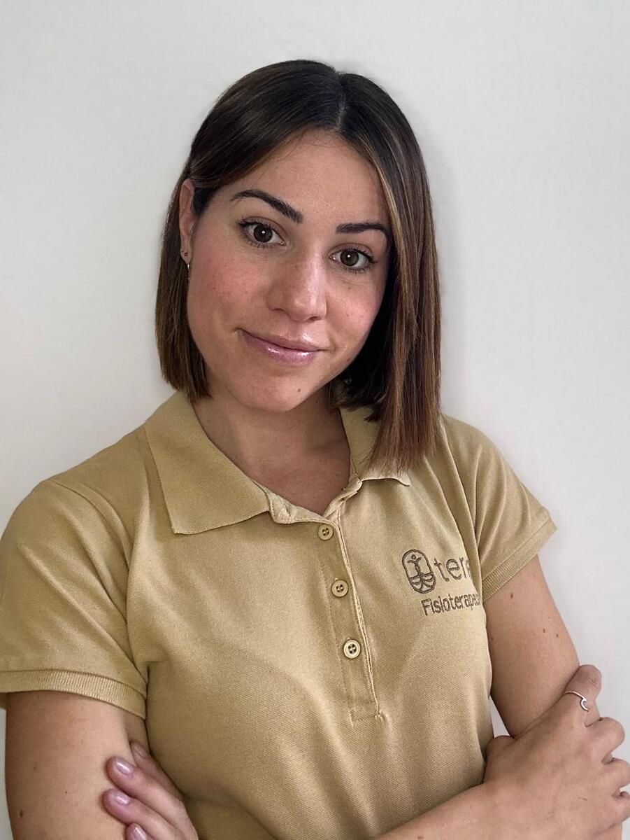 Mujer con cabello castaño hasta los hombros, vistiendo un polo color canela, sonriendo levemente con los brazos cruzados.