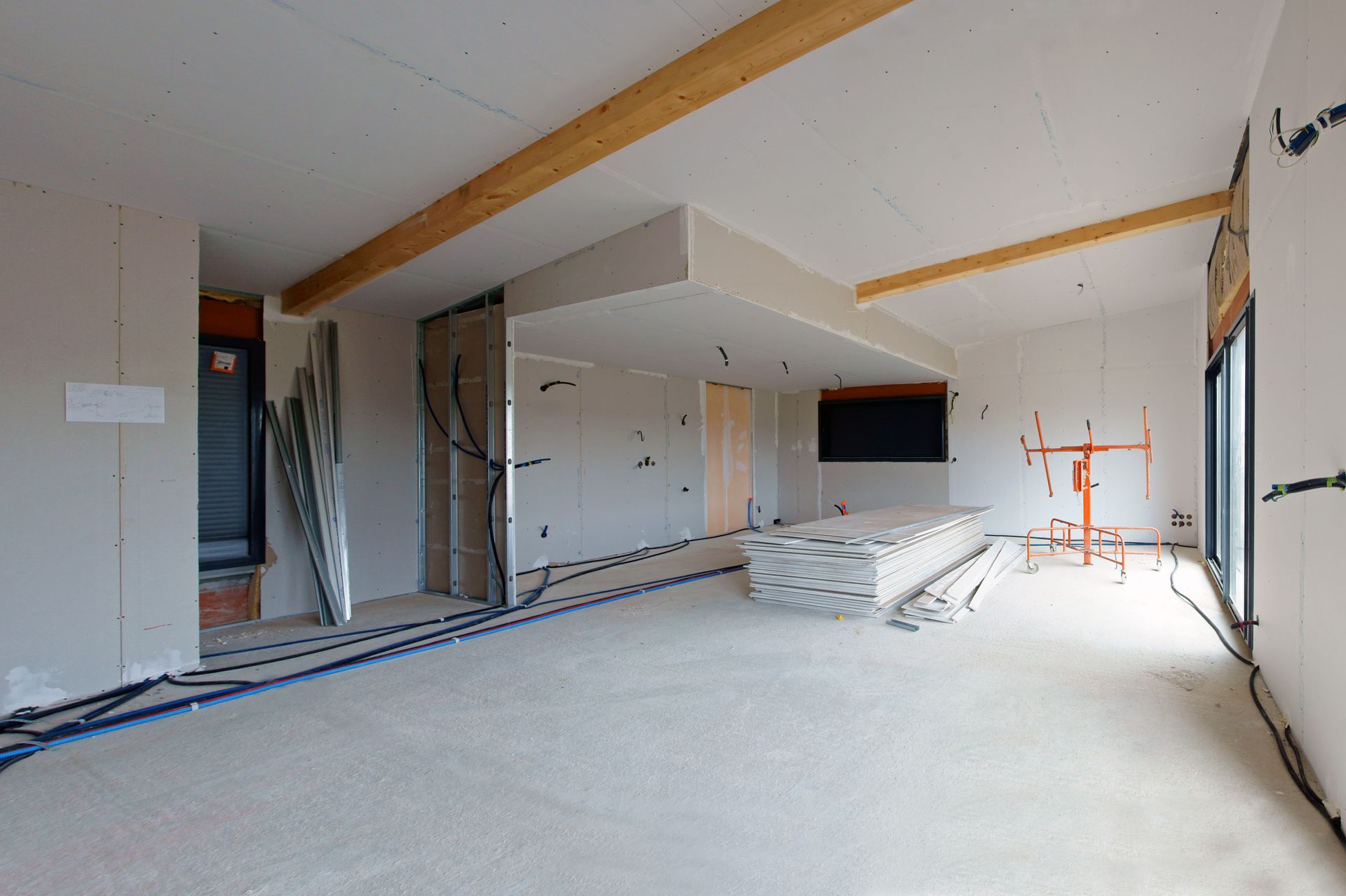 Pièce intérieure en cours de construction avec échelles, cloisons sèches et porte.