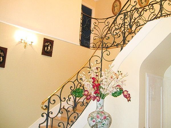 Escalier en colimaçon en bois sombre sur fond de murs blancs, menant vers le haut.