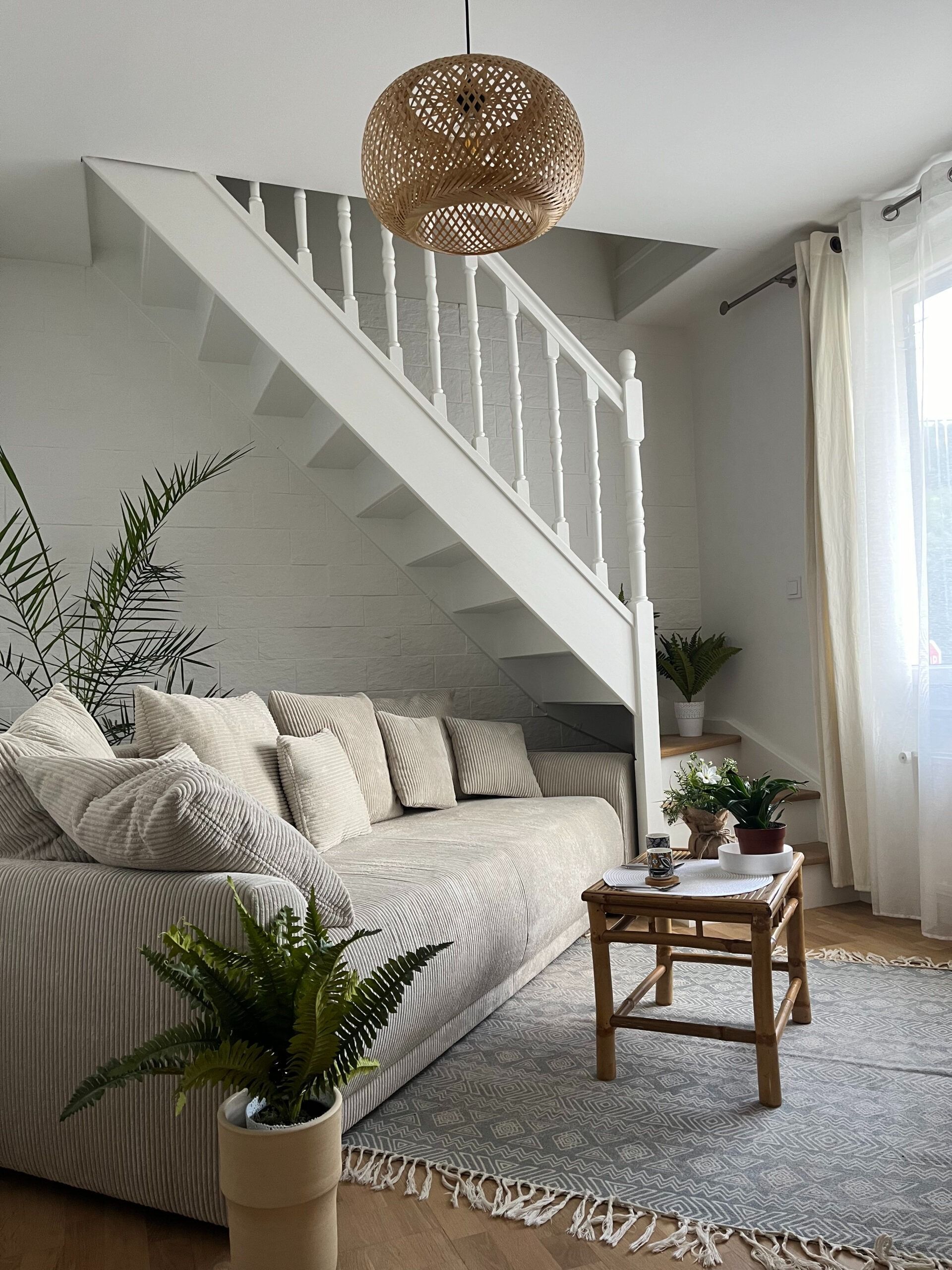 Escalier avec rampe ornée, tapis rouge, menant à une porte cintrée aux murs lambrissés.
