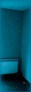 Habitación vacía de color azul en una esquina, con un radiador blanco cerca del suelo.