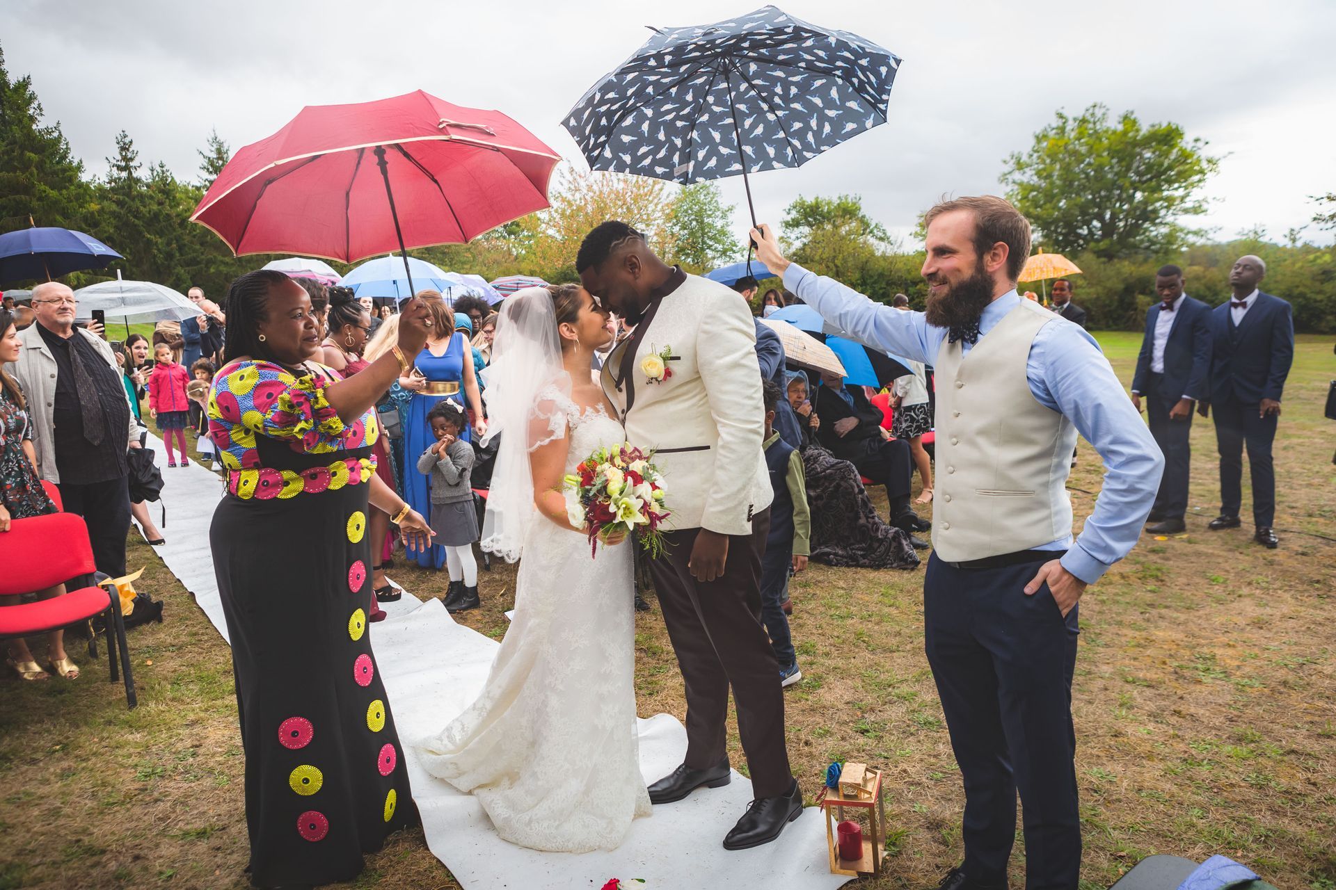 Mariés avec des invités qui tiennent un parapluie
