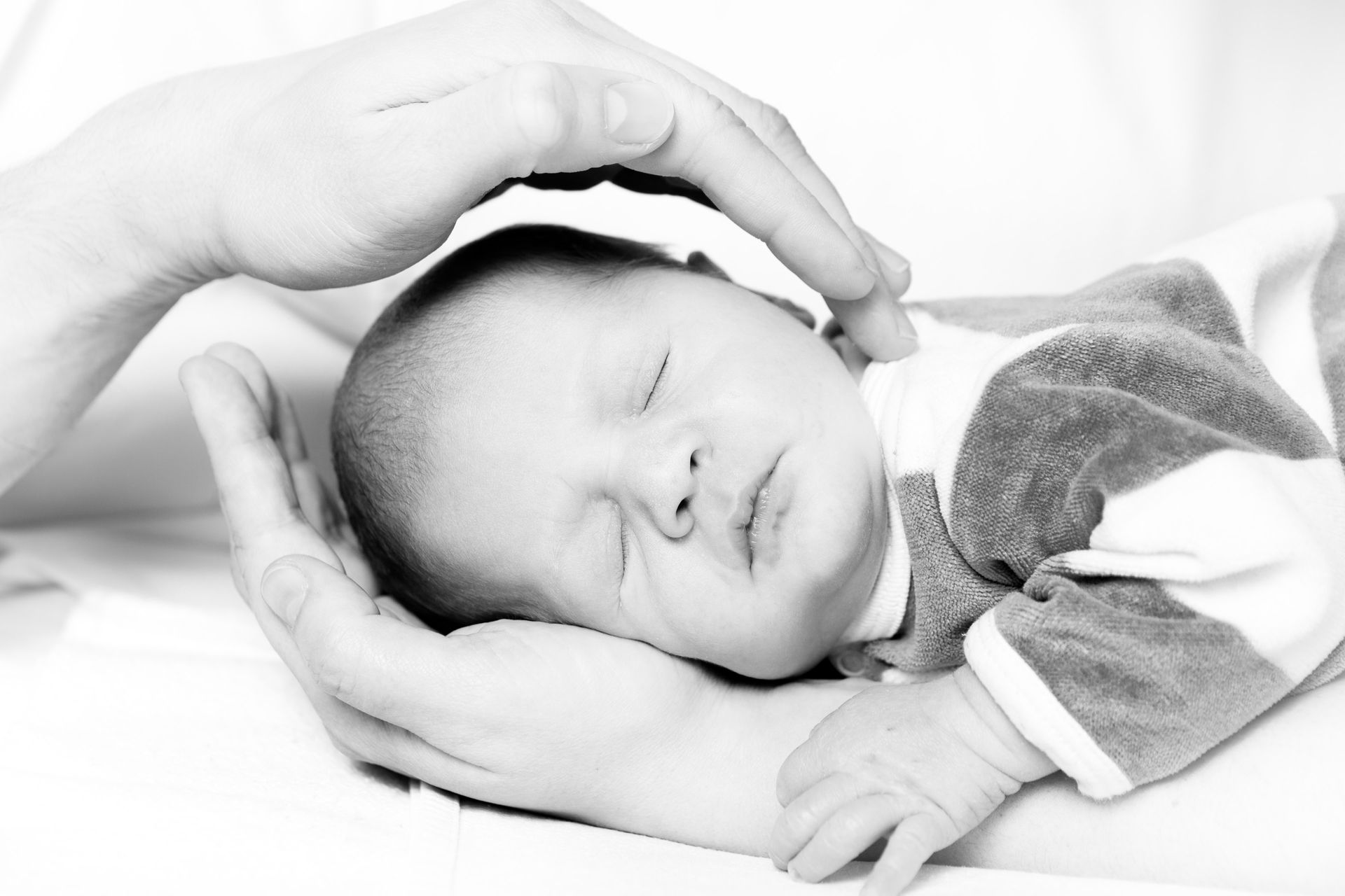 Bébé qui dort dans une main avec une main au-dessus de lui