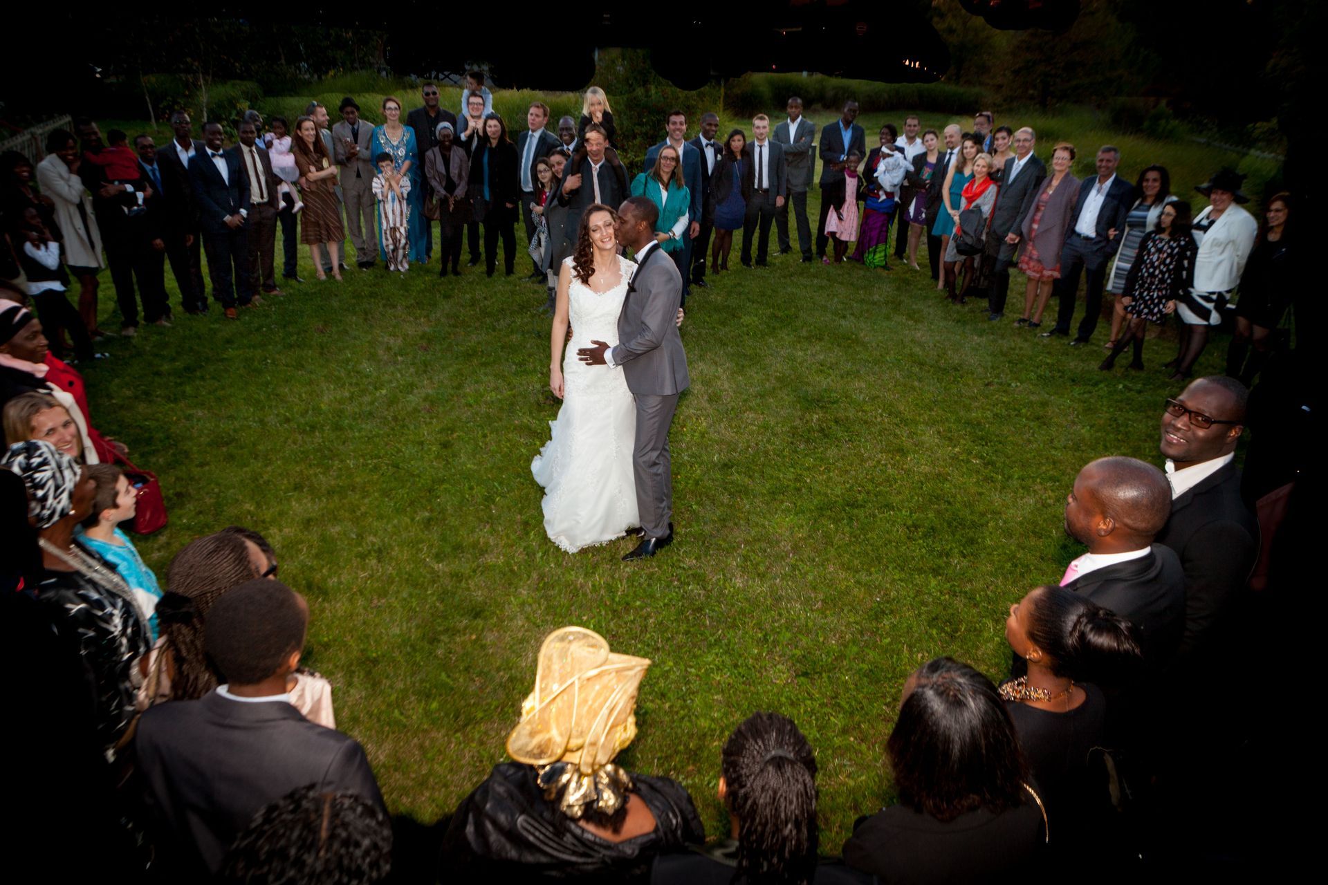 Mariés qui s'embrassent au milieu des invités qui forment un cœur