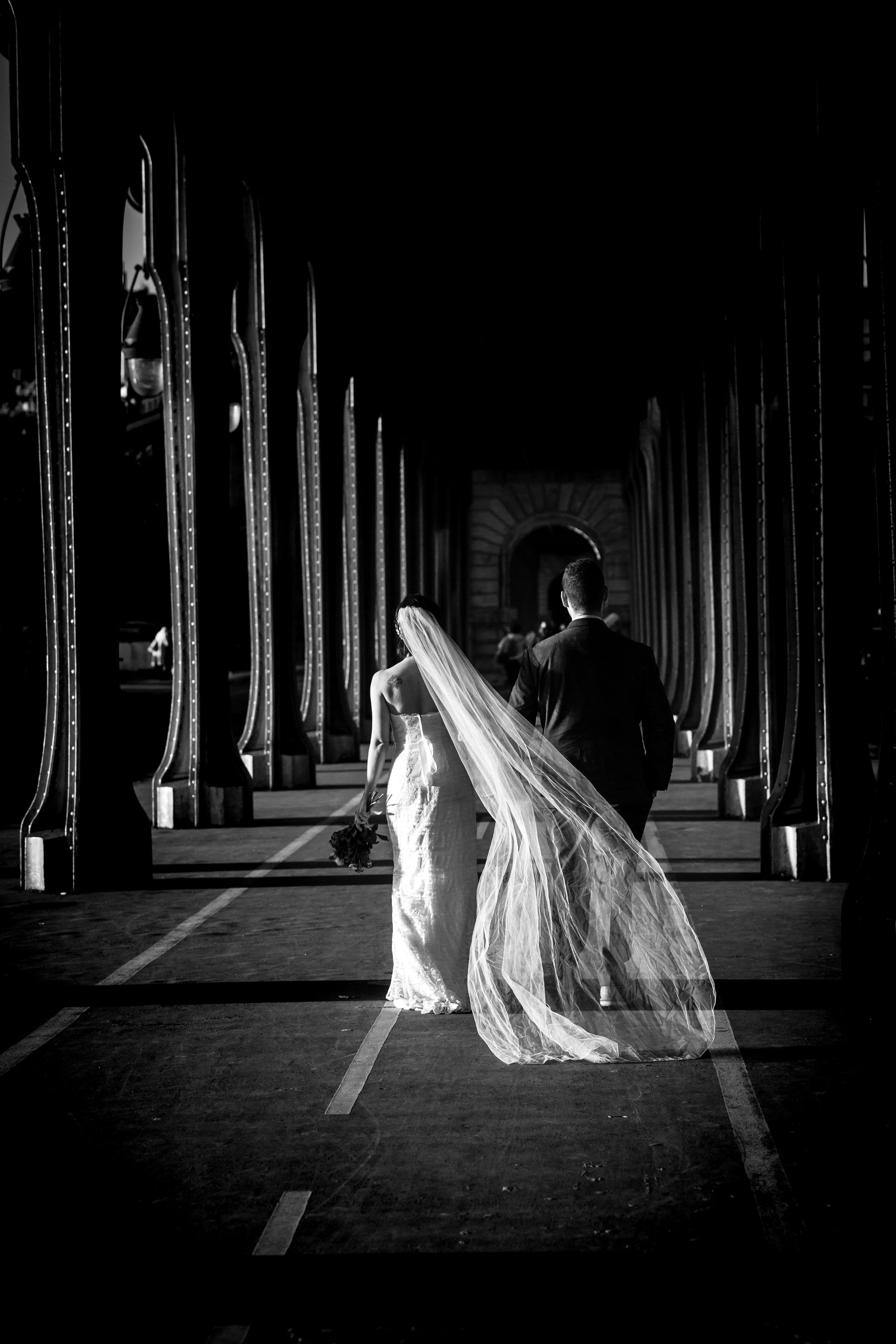 Mariés qui marchent sous un pont