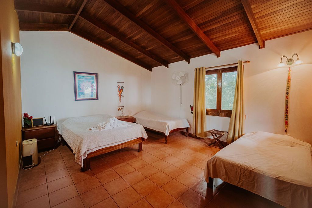 A bedroom with three beds and a wooden ceiling.
