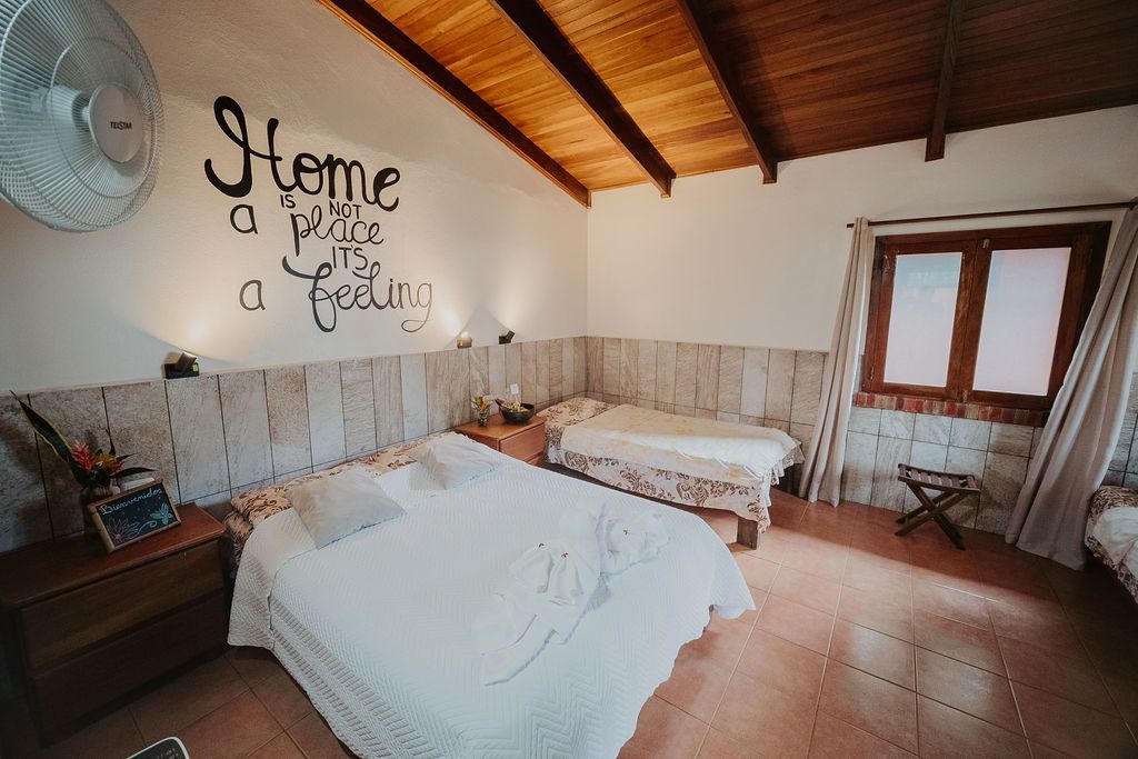 A bedroom with two beds and a sign on the wall that says home is a feeling.