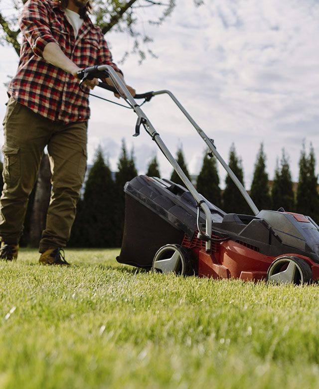 Un hombre está cortando el césped con una cortadora de césped.
