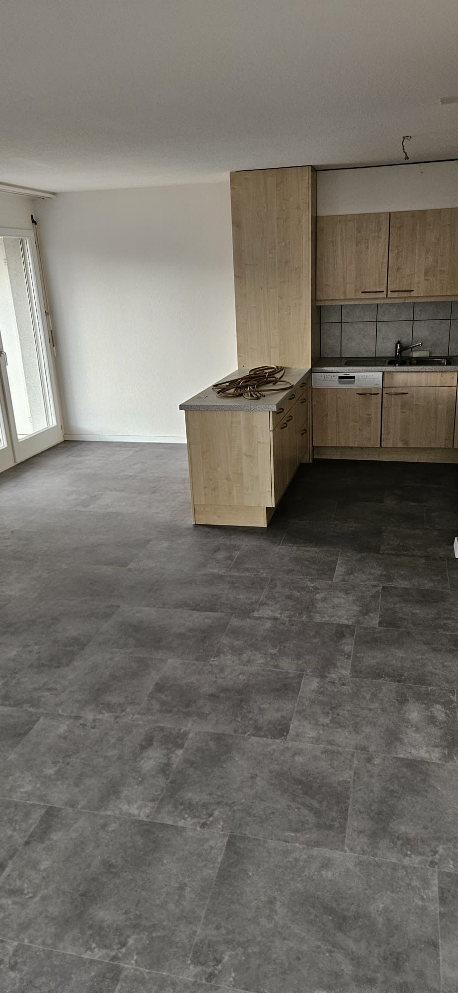 Une pièce en rénovation avec un nouveau parquet clair posé et des cartons Bauwerk empilés au sol.