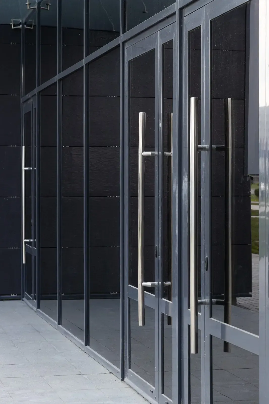 Puertas de vidrio con manijas plateadas en la fachada de un edificio oscuro.
