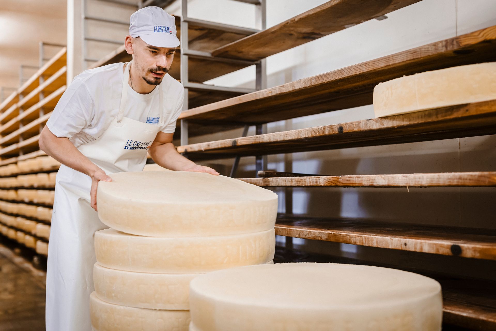Une personne en uniforme blanc dans une boulangerie avec de hautes étagères à plateaux.