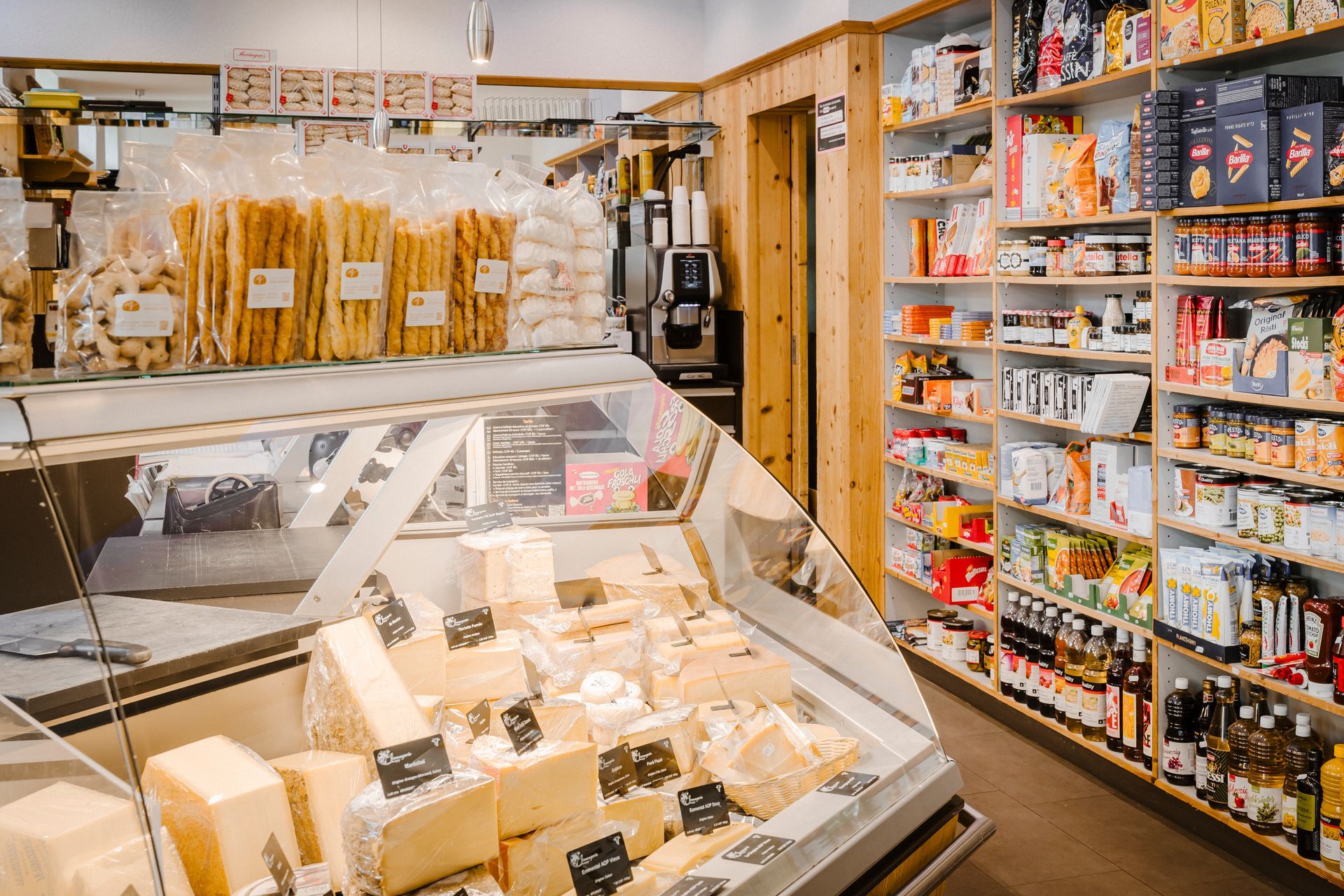 Gros plan sur des meules de fromage à pâte dure empilées sur des étagères en bois dans une cave.