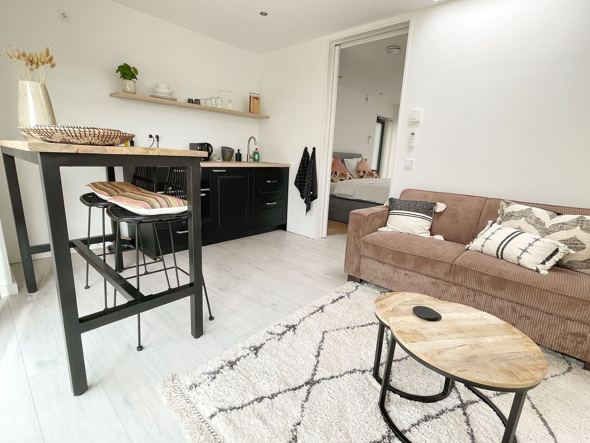 Petit appartement moderne avec cuisine, coin salon et table haute.