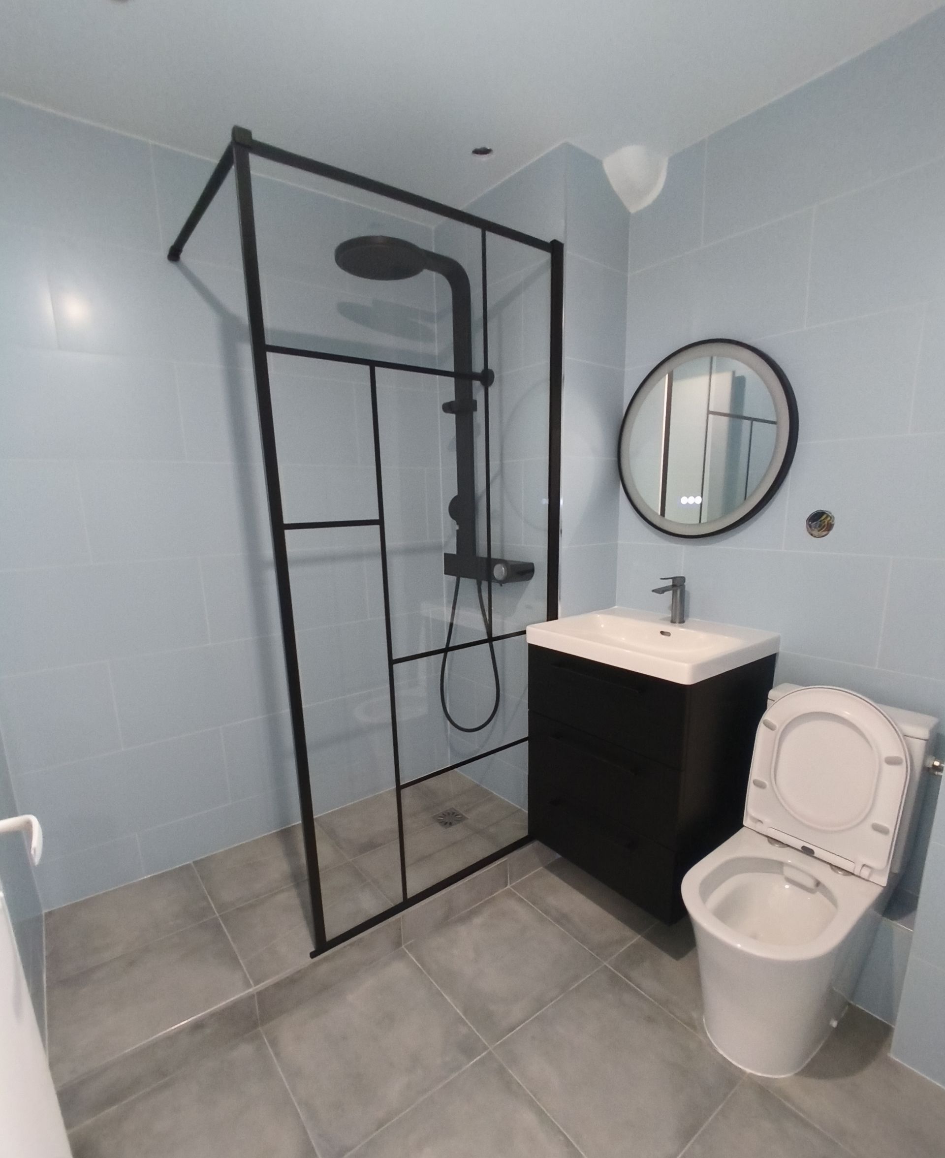 Salle de bains moderne avec douche, lavabo, miroir et toilettes.