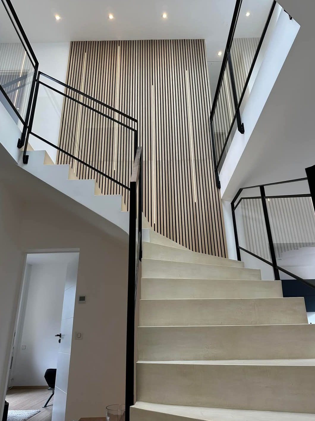 Entrée d'une maison aux murs de pierre, avec escalier.