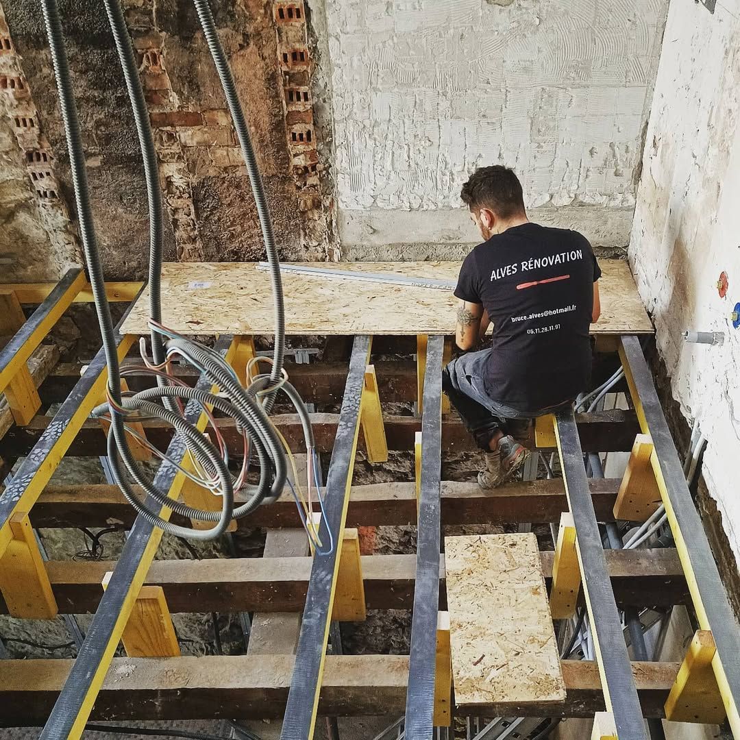 Un ouvrier du bâtiment installe des lames de parquet.