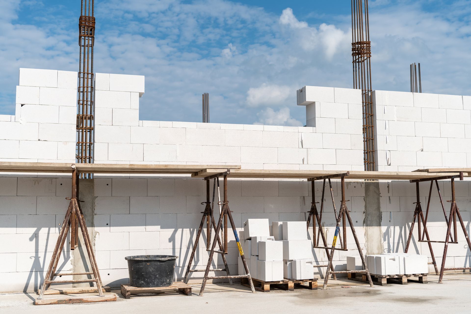 Baustelle: weiße Zementsteinwände, Gerüst, Stahlträger, blauer Himmel.