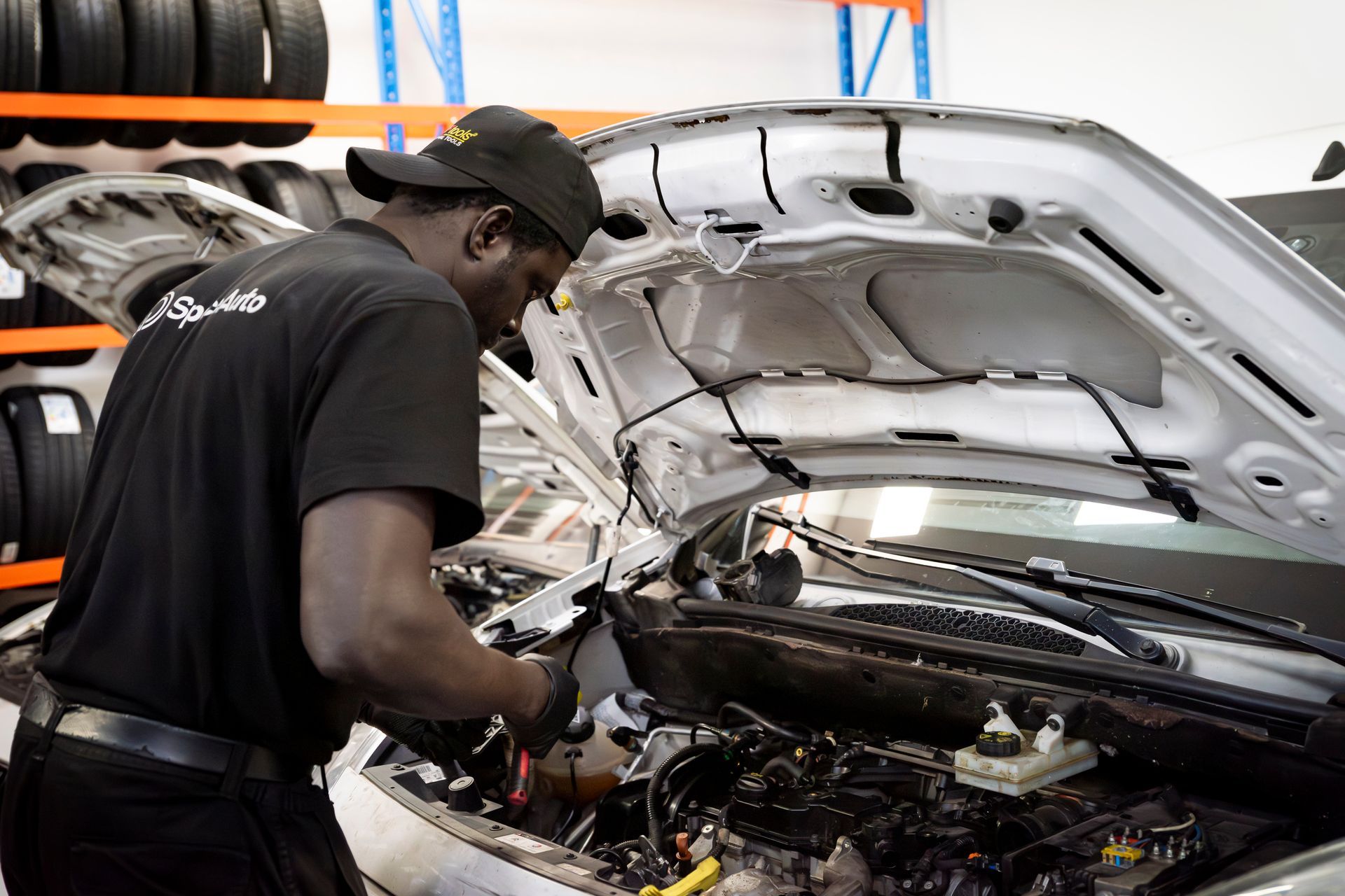 Employé de SpaceAuto en train de vérifier le moteur d'une voiture