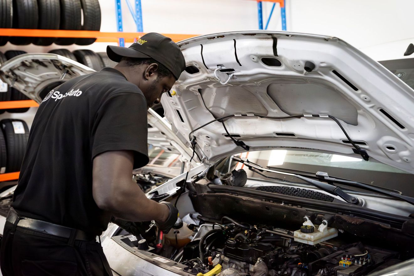 Employé de SpaceAuto en train de vérifier le moteur d'une voiture