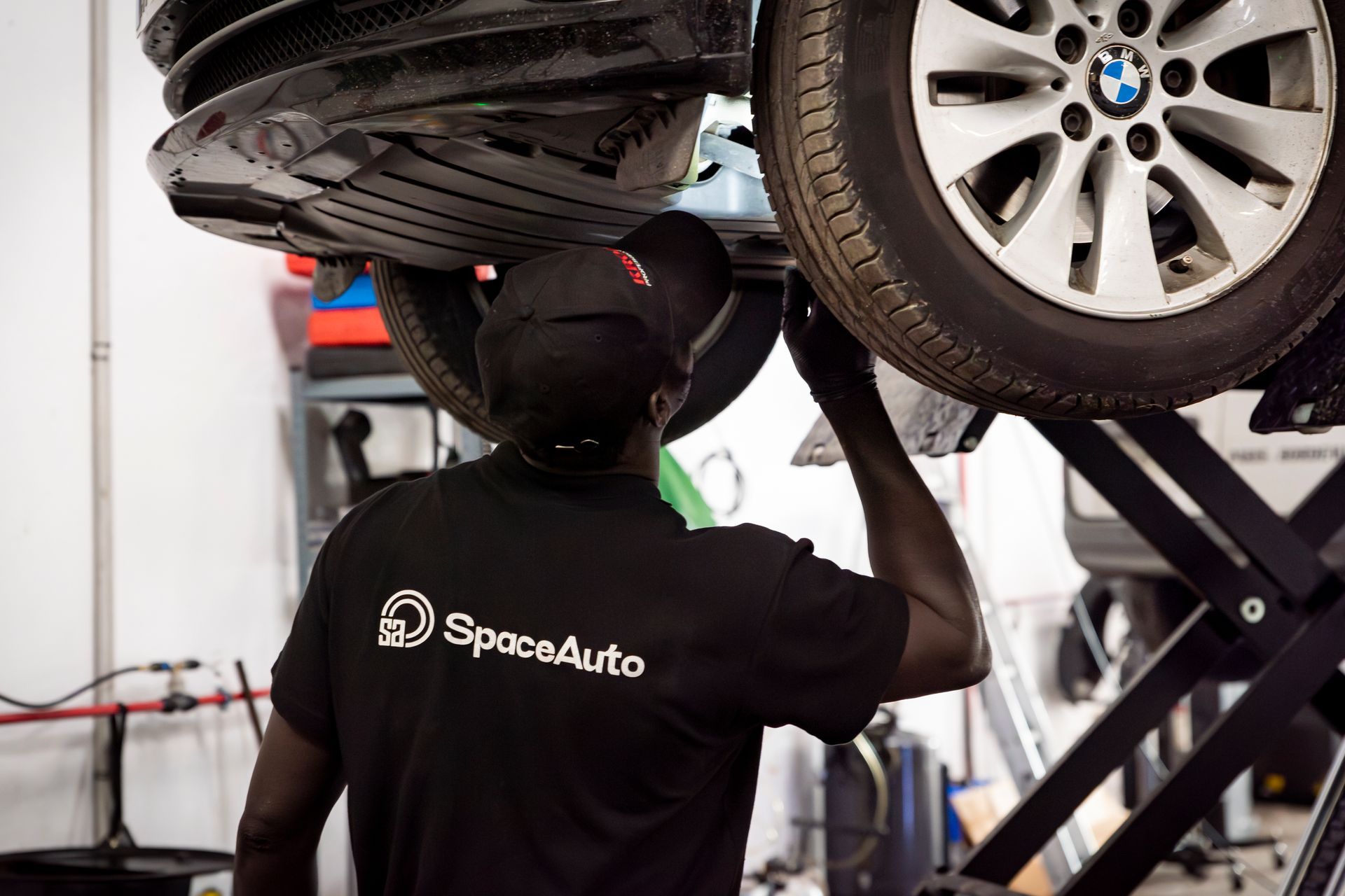 Garagiste qui inspecte le dessous d'une voiture avec une lampe