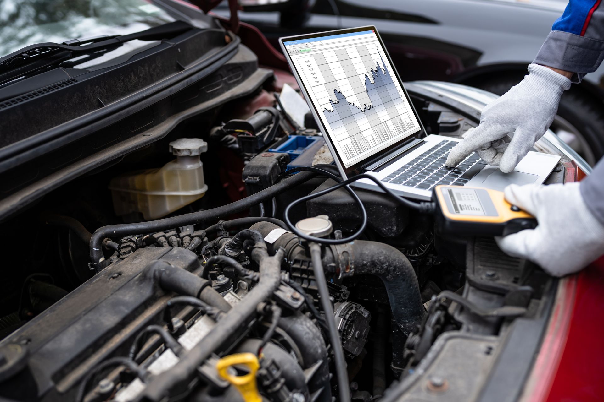 Garagiste qui fait le diagnostic moteur d'une voiture à l'aide d'une valise