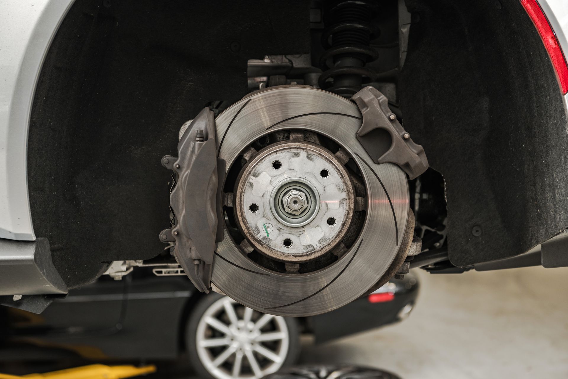 Ensemble de rotor de frein de voiture, étrier gris, disque et moyeu, dans un environnement d'atelier.