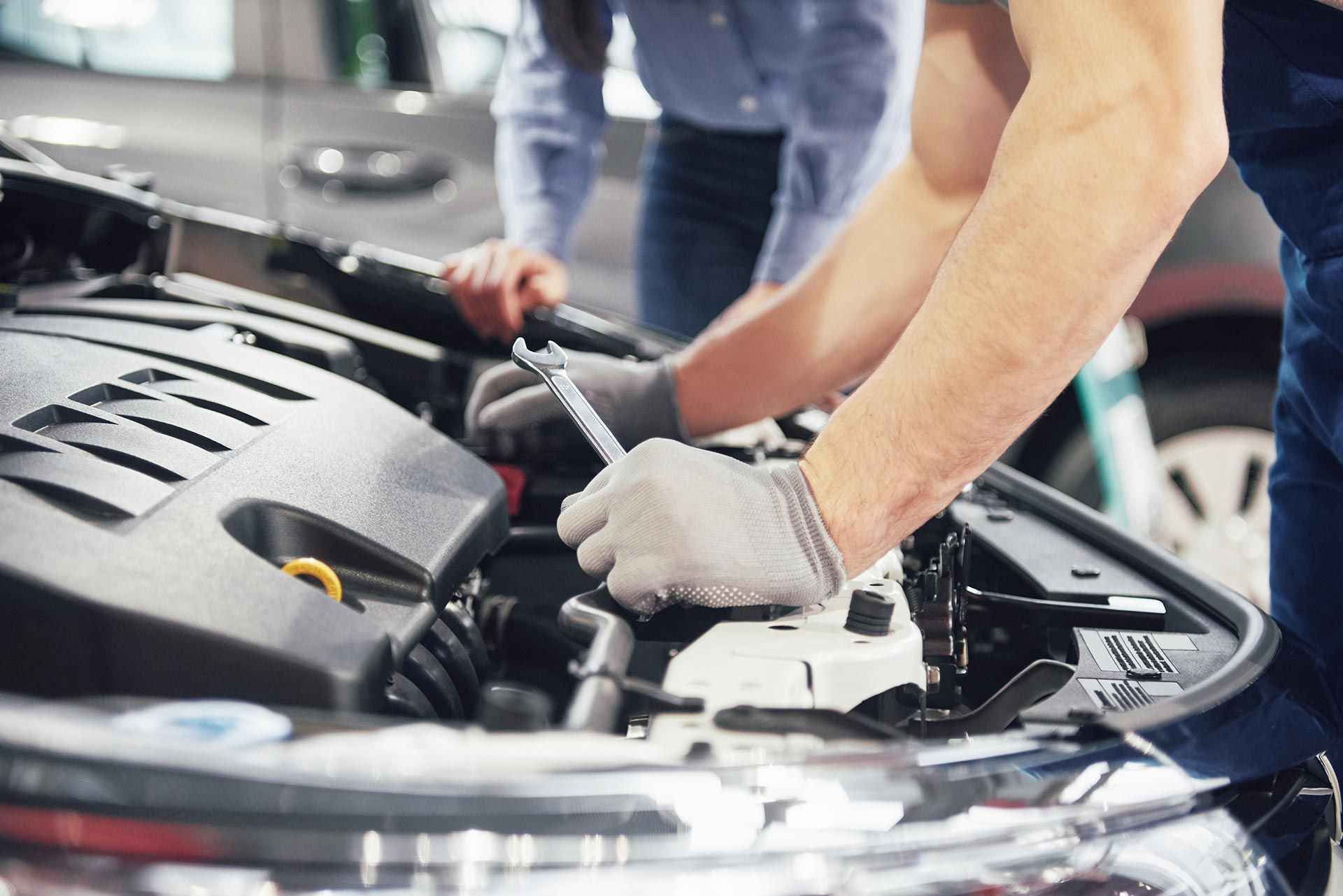 Homme qui inspecte un moteur avec une clé dans la main