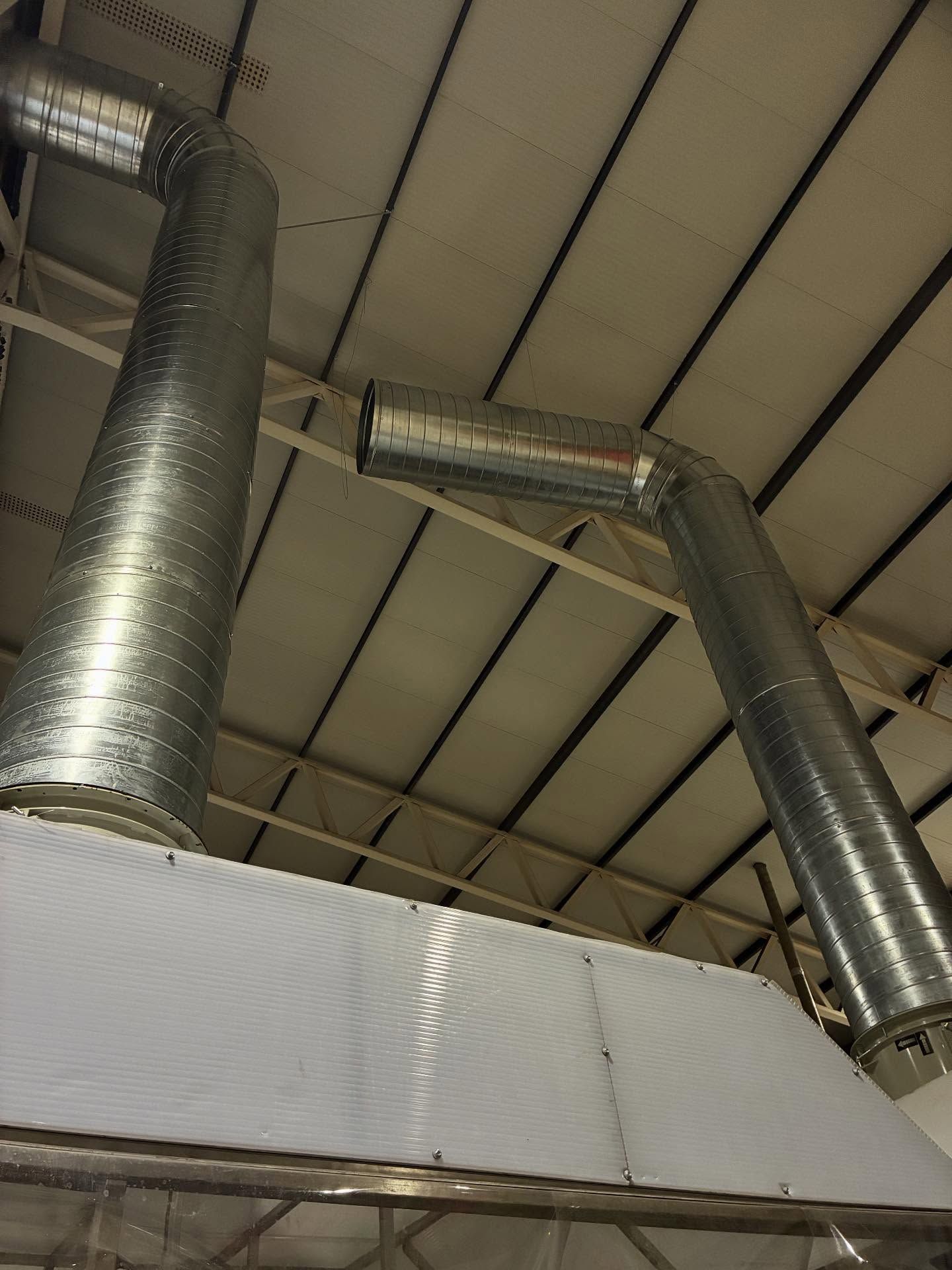 Techo industrial con conductos de ventilación plateados y brillantes y paneles blancos arriba