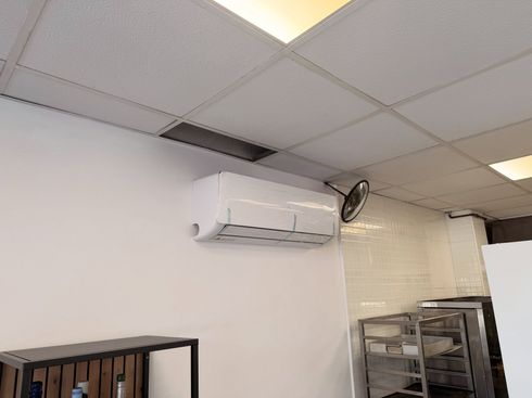 Interior de oficina con aire acondicionado de pared, luces en el techo y estanterías de almacenamiento