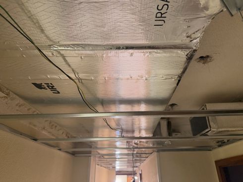 Conductos de aire y tuberías metálicos que recorren el techo de un pasillo industrial sin terminar.