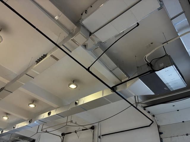 Techo con conductos, tuberías y luces a la vista en un interior de estilo industrial