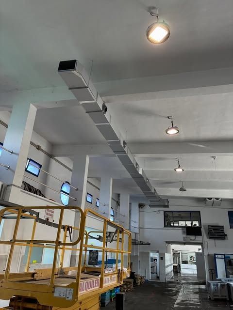 Interior de una nave industrial con plataformas metálicas amarillas, luces de techo alto y una amplia zona de trabajo abierta