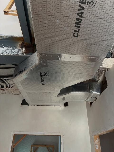 Conductos de climatización aislados en un techo sin terminar, envueltos en papel de aluminio plateado