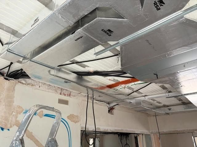 Techo dañado con aislamiento expuesto, cables colgando y una escalera en una habitación en reparación