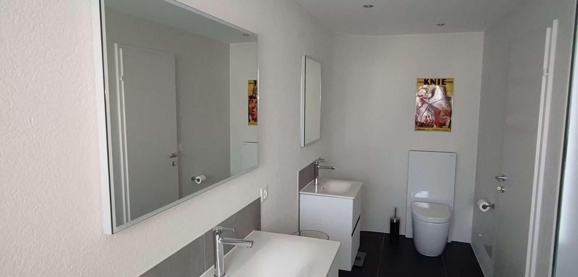 Modernes WC mit Waschbecken, Spiegel und Toilette in einem sauberen, grauen Interieur