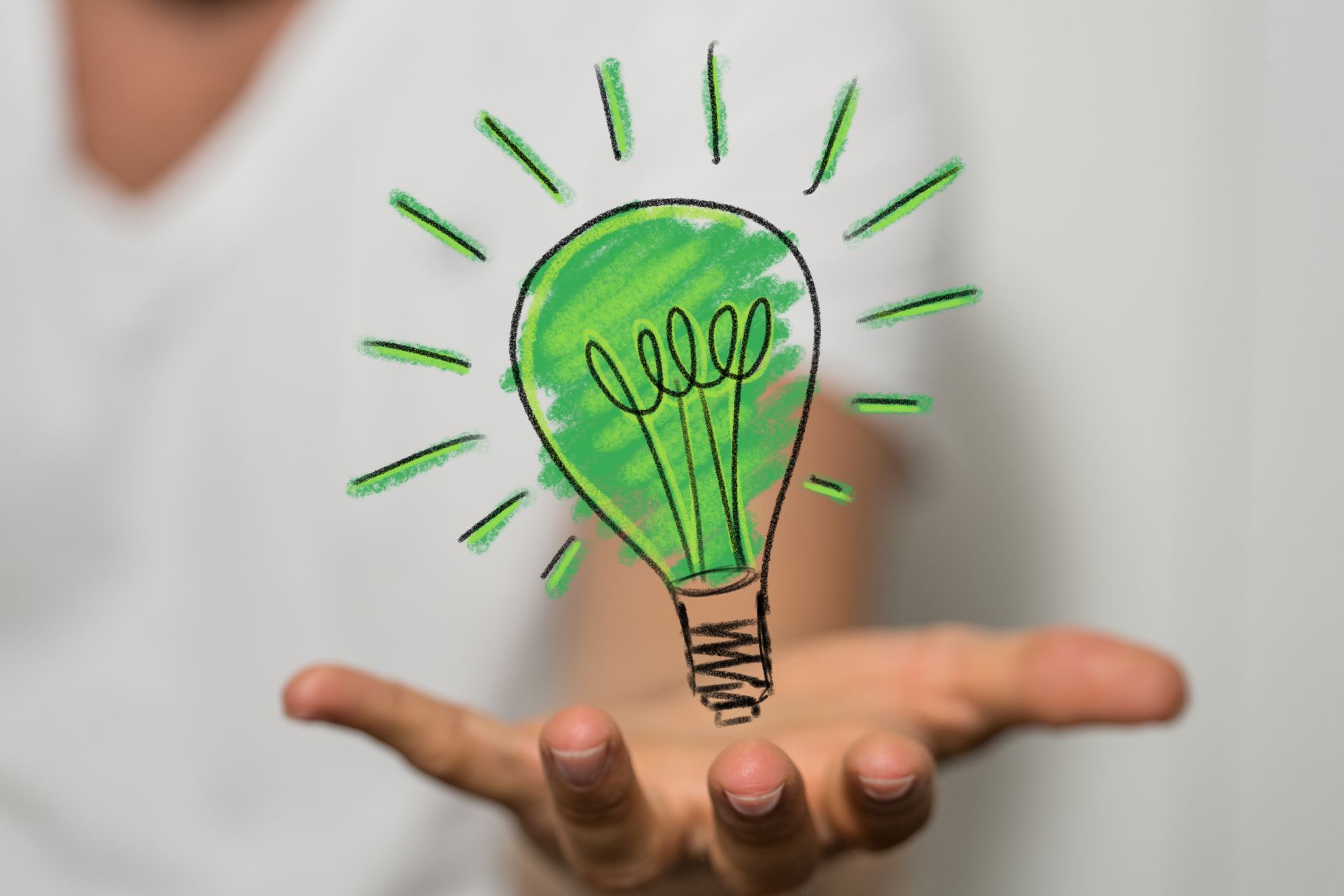 Main tenant une ampoule verte lumineuse avec des rayons, symbolisant une idée nouvelle.
