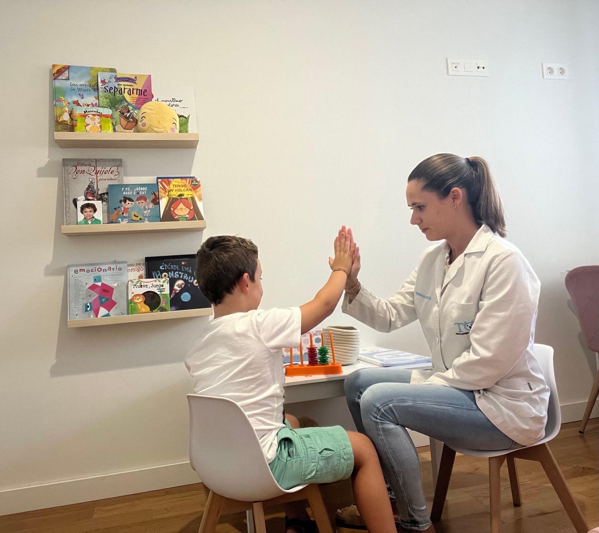 Un niño choca los cinco con un profesional médico en una habitación con una estantería.