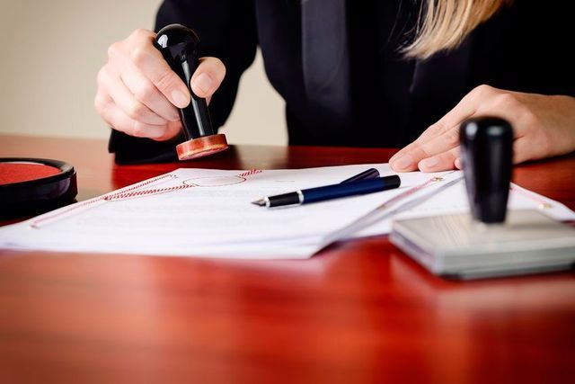 Una mujer está estampando un documento en una mesa.