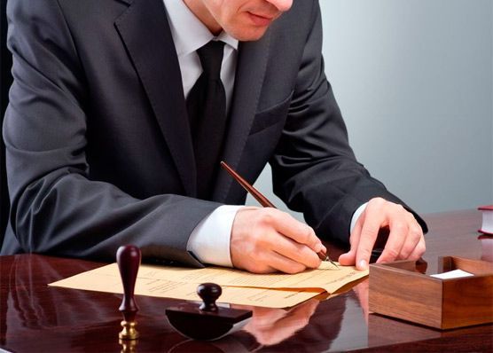 Un hombre con traje y corbata está escribiendo en un trozo de papel.
