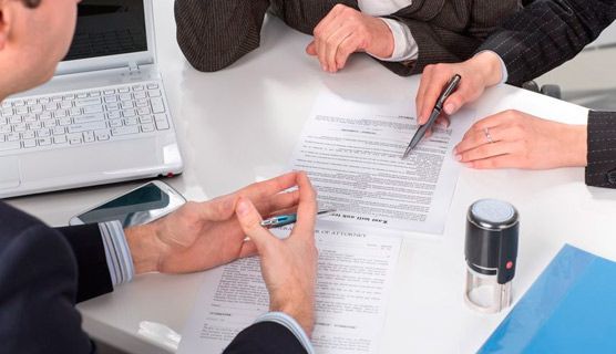 Un grupo de personas está sentada en una mesa firmando un documento.