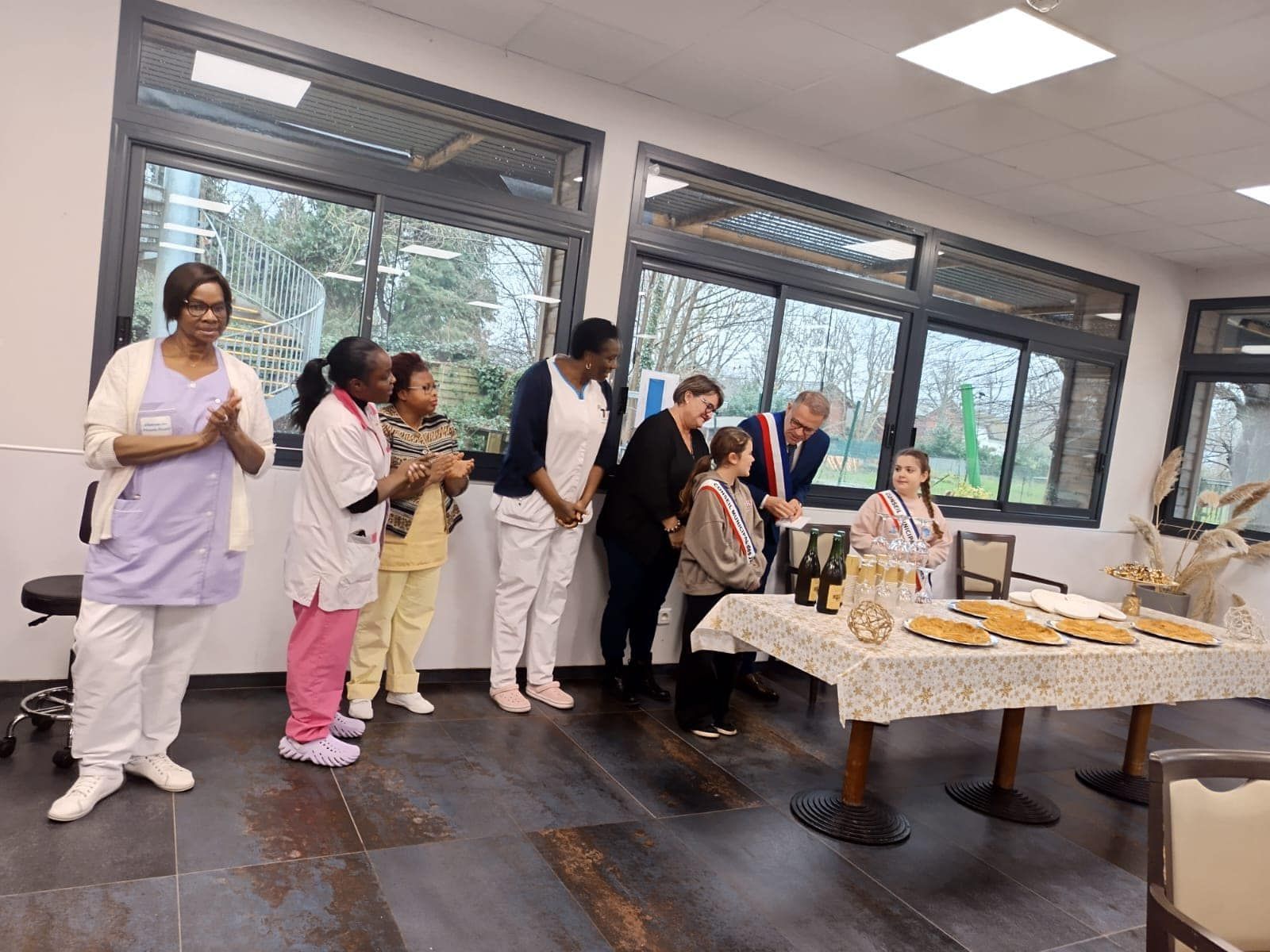Des personnes en blouse blanche se tiennent près d'une table de nourriture lors d'un événement lumineux en intérieur
